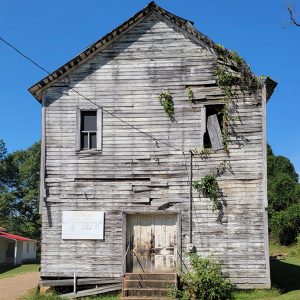 Multistory abandoned and dilapidated wooden building with Masonic sign on front