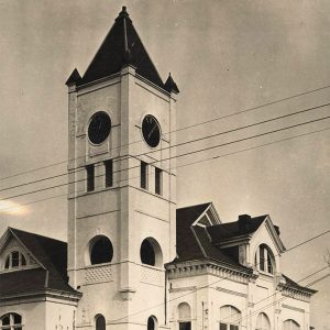 Multistory white granite building with tall corner clock tower