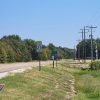 country road with trees on one side and a few buildings on the other with sign saying "Palestine"