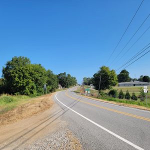 Country road curving through tiny community with trees on both sides