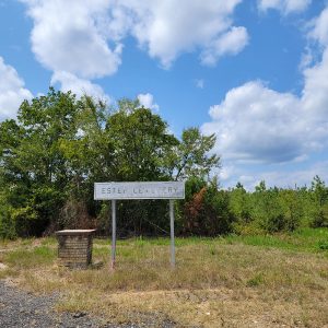 Faded sign beside brick column saying "Estep Cemetery