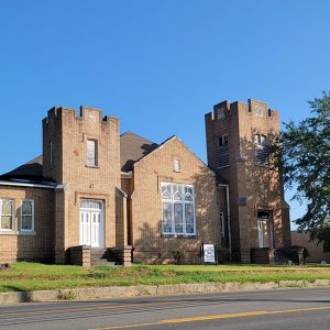 Multistory tan brick church building with two towers of differing heights