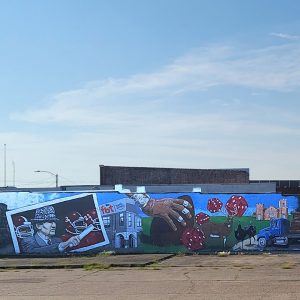 Mural painted on brick wall with various people and objects including a deer