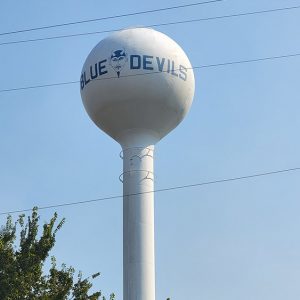 tall white water tower saying "Blue Devils" with devil head