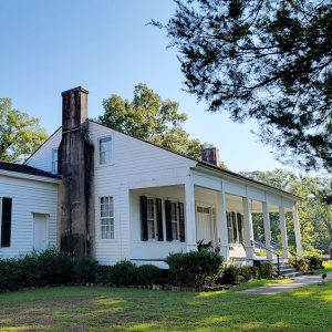 Multistory white wooden house with front porch and two chimneys