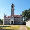 Multistory light brown brick building with red roof and large clock tower