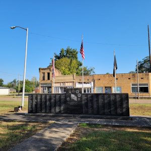 black marble monument with names inscribed and several flags behind it