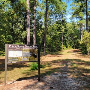 Trailhead amid trees with sign saying "Poison Spring Nature Trail"