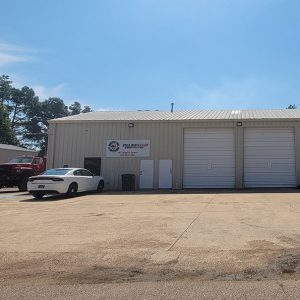 Single story beige metal building with four garage bay doors