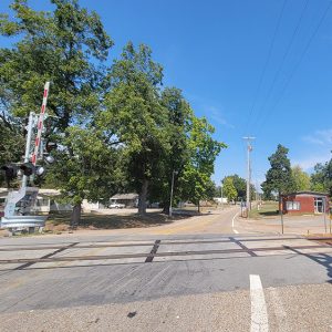 Small town street with houses and a railroad crossing and trees