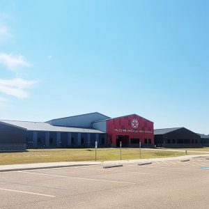 Row of school buildings constructed from a variety of materials with one building having a red front with a star