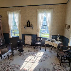 Wallpapered room with antique furnishings and white curtains