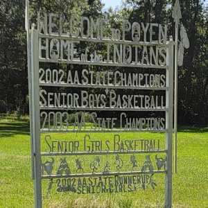 Metal sign listing team sports accomplishments with trees in background