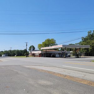 Small town street scene with businesses and a couple of vehicles