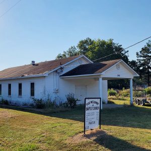 Single story white concrete block church building with covered entrance