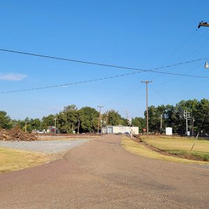 road going over railroad tracks next to large pile of wood and brush