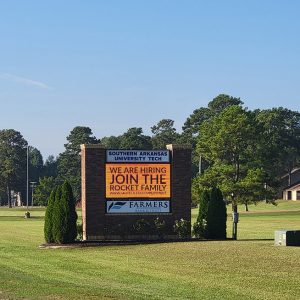 Southern Arkansas University Tech sign with electronic screen with trees and buildings in background