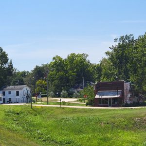 Small town street scene with houses and businesses in distance amid trees