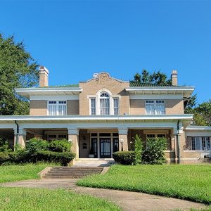 Multistory tan brick house with extensive covered front porch