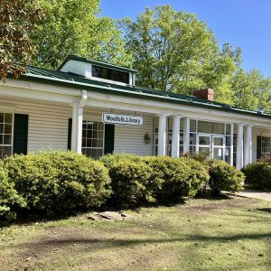 Single story white wooden library building with white pillars on covered porch