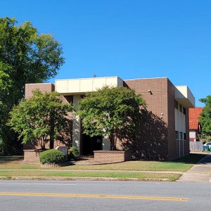 Multistory red brick building on streetcorner with trees