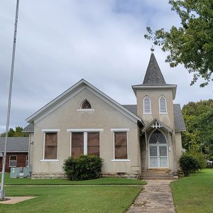 Multistory off-white stucco church building with small tower and covered entrance