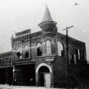 Multistory granite building with bays and a conical protrusion on the roof