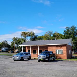 Single story orange brick building with vehicles parked in front