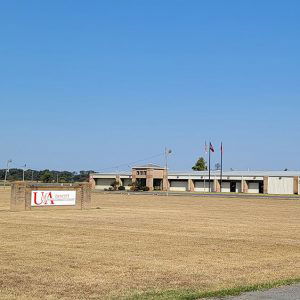 Long row of single story tan brick and metal school buildings