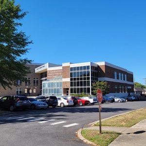 Multistory orange brick building with wall of windows in front