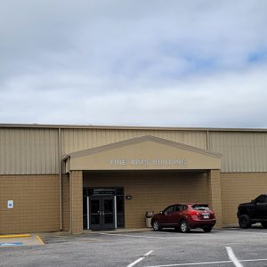 Single story yellow metal and brick building with parking lot