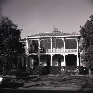 Two story white wooden house with porch on each floor and pillars