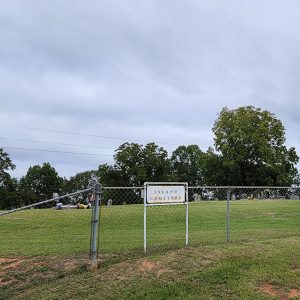 Cemetery with chain link fence and gravestones and trees