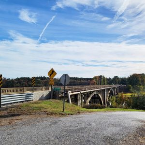 Concrete arched bridge spanning small part of a lake