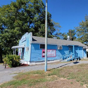 Single story blue wooden building with ramp leading to side door