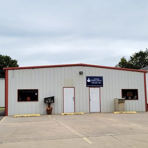 Single story white metal building "Lavaca Public Library" with parking lot