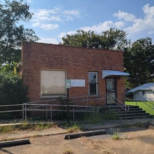 Single story red brick post office building with small white awning