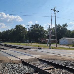 Small town street with a few buildings and a railroad crossing