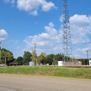 Small town street with a few buildings and railroad tracks and crossing and trees