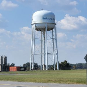 metal water tank on tall legs with small buildings underneath