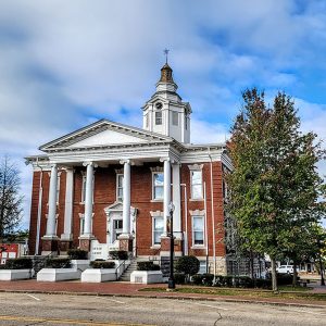 Multistory red brick building with Greek columns and white brick clock tower