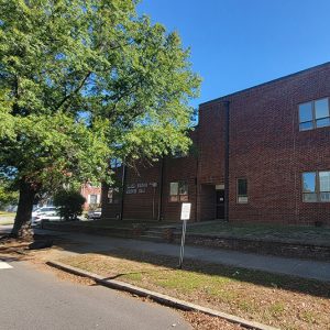 Multistory red brick building next to sidewalk