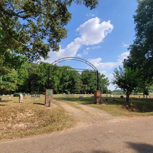 cemetery with graves and trees and an arched entrance