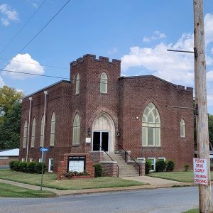 Multistory brown brick church building with stairs leading to corner entrance