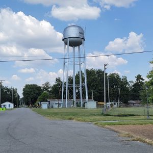 metal water tank on tall legs with small buildings underneath