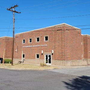 Multistory red brick building with a base of stone blocks on street corner