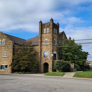 Multistory rock church building with tower next to street