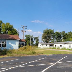 dilapidated buildings next to parking lot with trees