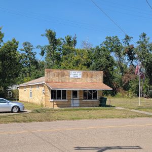 Single story yellow brick post office building with awning