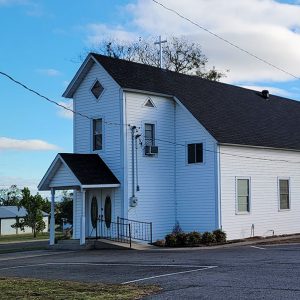 Multistory white wooden church building with parking lot